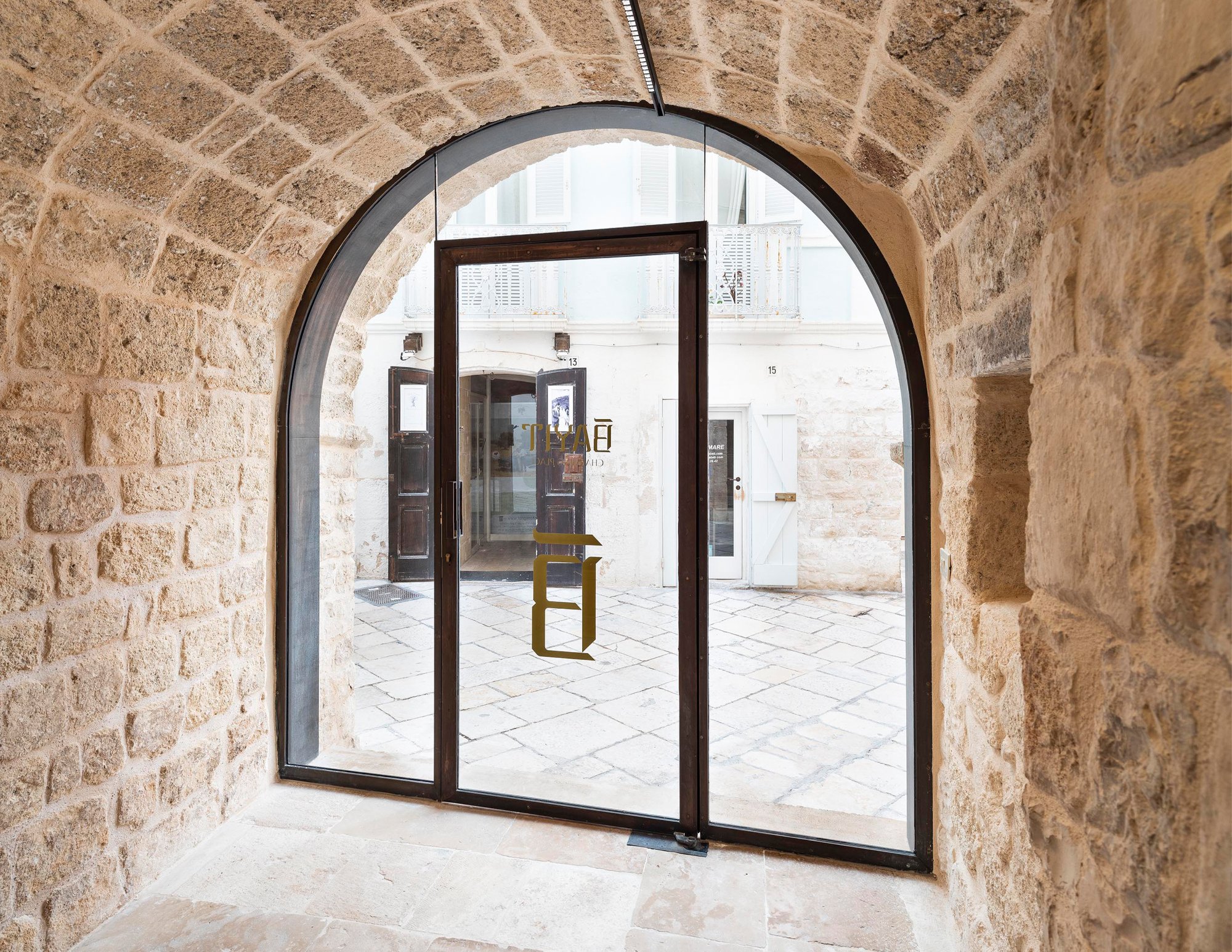 Custom arched bronze-and-glass entry in a Southwest Florida stone courtyard