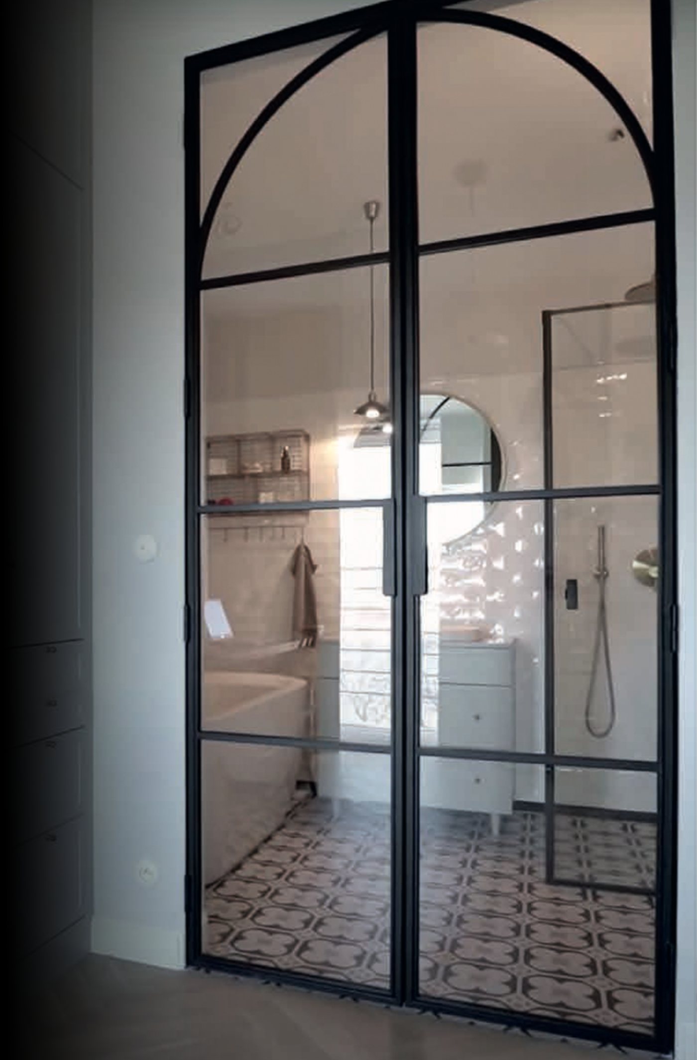 Arched black steel-look interior glass double doors opening to a bathroom